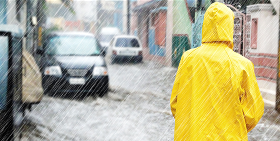 Frau im Regenmantel bei Hochwasser in der Stadt